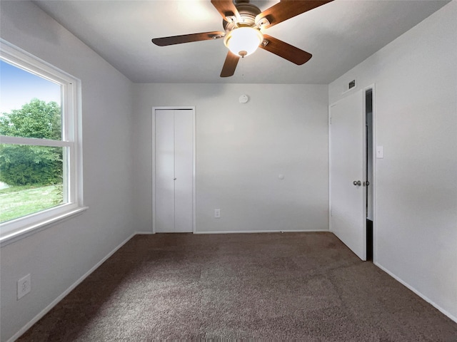 carpeted spare room featuring ceiling fan and plenty of natural light