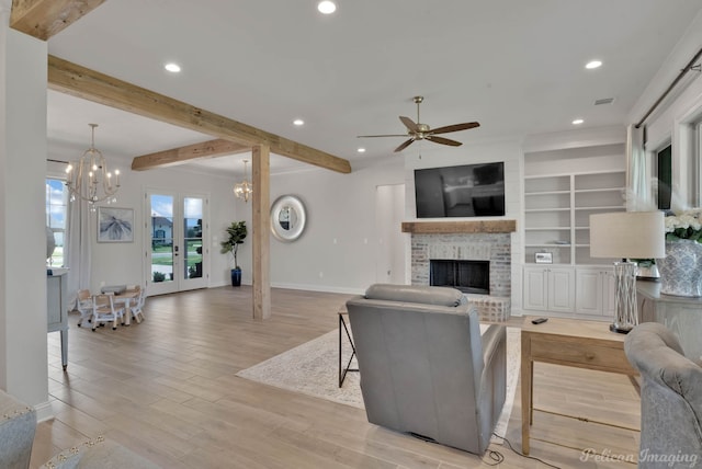 living room with light wood-type flooring, a fireplace, ceiling fan with notable chandelier, french doors, and beam ceiling