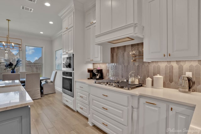 kitchen with decorative backsplash, hanging light fixtures, light wood-type flooring, white cabinetry, and appliances with stainless steel finishes