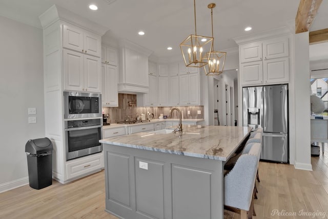 kitchen with beamed ceiling, light hardwood / wood-style flooring, stainless steel appliances, light stone countertops, and white cabinets