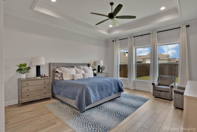 bedroom with ornamental molding, a tray ceiling, light hardwood / wood-style floors, and ceiling fan