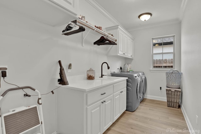 laundry area featuring cabinets, washer and dryer, light wood-type flooring, ornamental molding, and sink