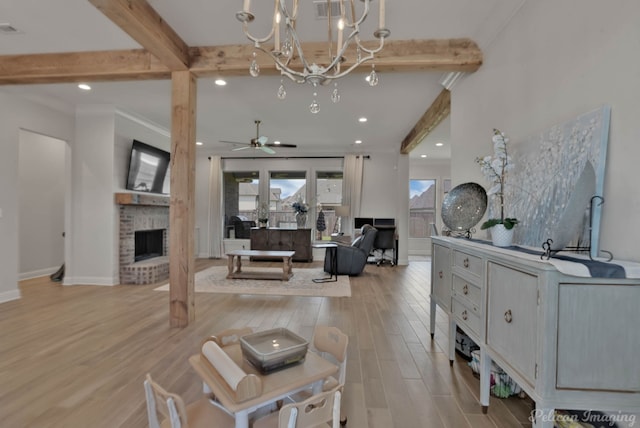 living room featuring crown molding, ceiling fan with notable chandelier, a fireplace, beam ceiling, and light hardwood / wood-style flooring