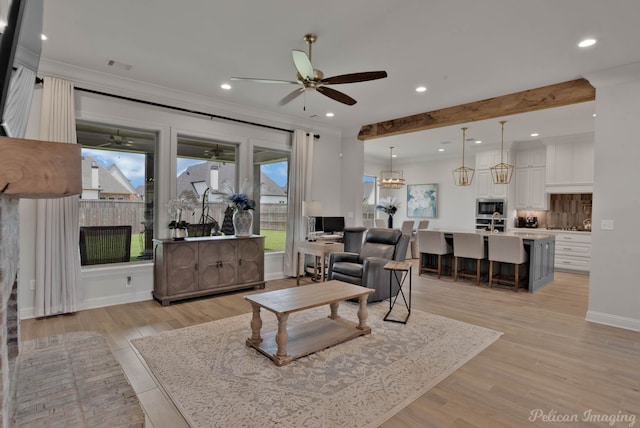 living room featuring light hardwood / wood-style flooring, ornamental molding, beam ceiling, and ceiling fan with notable chandelier