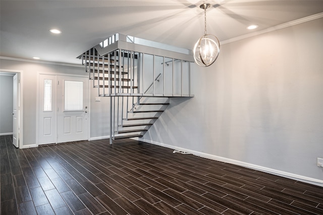 entryway with ornamental molding, dark hardwood / wood-style flooring, and a notable chandelier