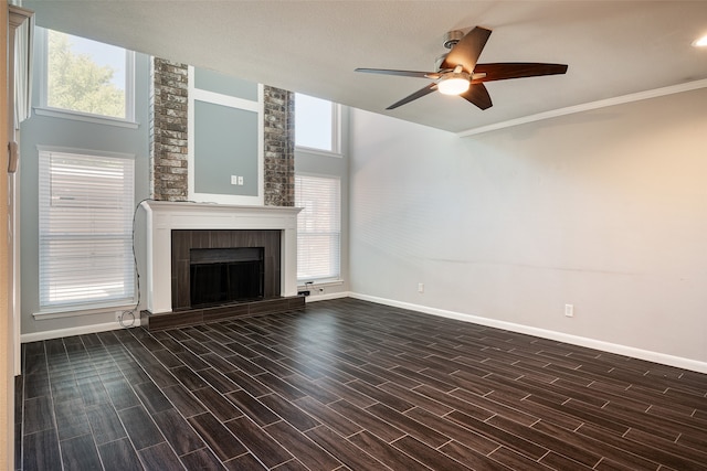 unfurnished living room with ceiling fan, dark hardwood / wood-style floors, a fireplace, and crown molding