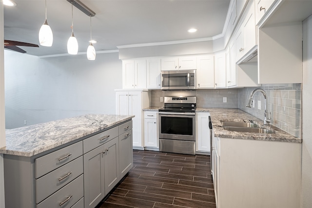 kitchen featuring sink, decorative light fixtures, white cabinetry, appliances with stainless steel finishes, and dark hardwood / wood-style floors