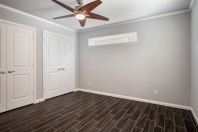 unfurnished bedroom with crown molding, two closets, dark hardwood / wood-style floors, and ceiling fan