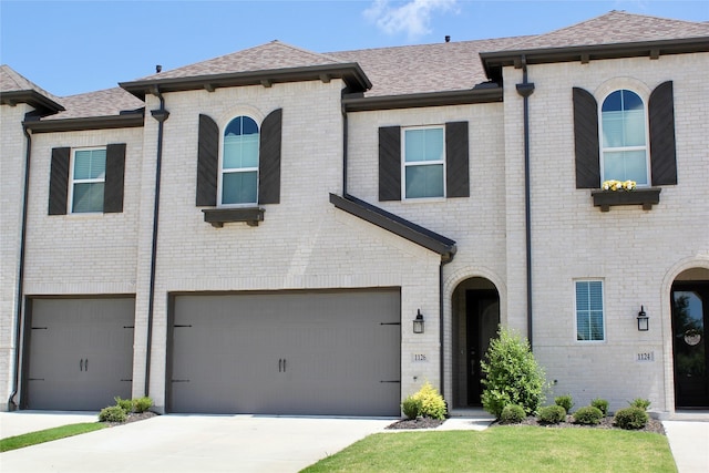 view of front facade featuring a garage, driveway, brick siding, and roof with shingles