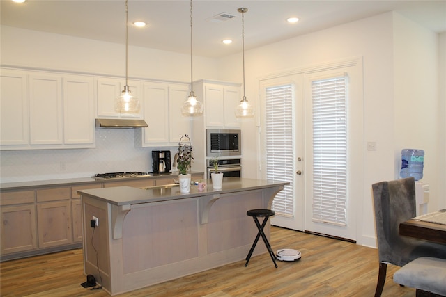 kitchen featuring stainless steel appliances, a kitchen island with sink, a breakfast bar area, and white cabinets