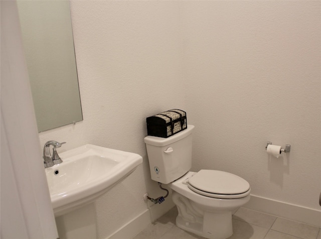 bathroom with sink, toilet, and tile patterned flooring