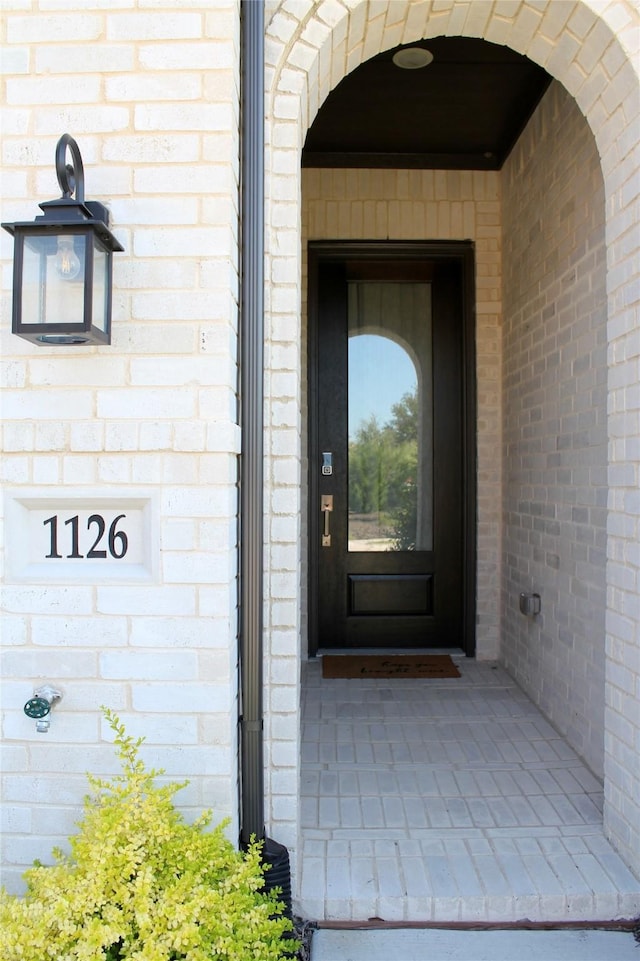 view of exterior entry featuring brick siding