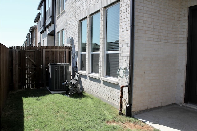 view of side of home featuring central AC and a lawn