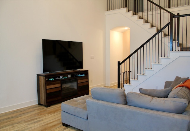 living room with hardwood / wood-style floors and a towering ceiling