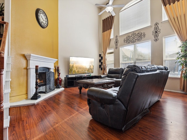 living room featuring hardwood / wood-style flooring, ceiling fan, and a high ceiling