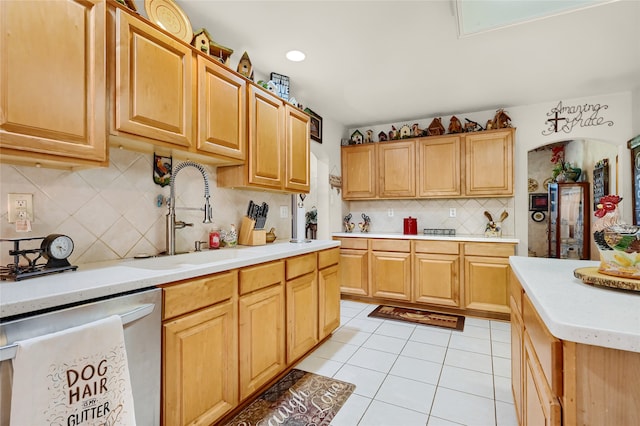 kitchen with light tile patterned floors, tasteful backsplash, light countertops, a sink, and dishwashing machine