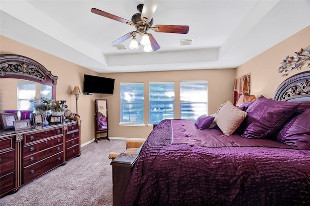 bedroom featuring light carpet, ceiling fan, and a raised ceiling