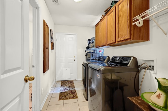 washroom featuring cabinet space, light tile patterned floors, baseboards, visible vents, and independent washer and dryer