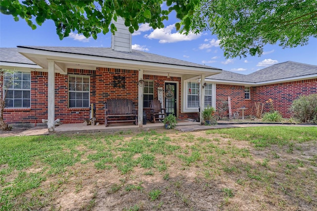 back of house featuring a lawn and covered porch