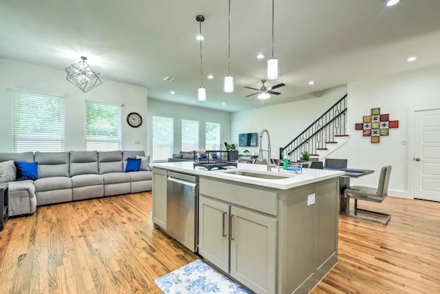 kitchen with gray cabinetry, ceiling fan, sink, stainless steel dishwasher, and a kitchen island with sink