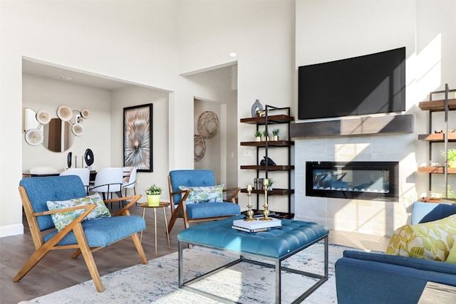 living room featuring a fireplace, wood-type flooring, and a high ceiling