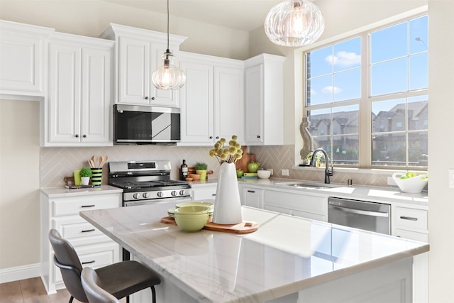 kitchen with pendant lighting, stainless steel appliances, backsplash, and white cabinetry