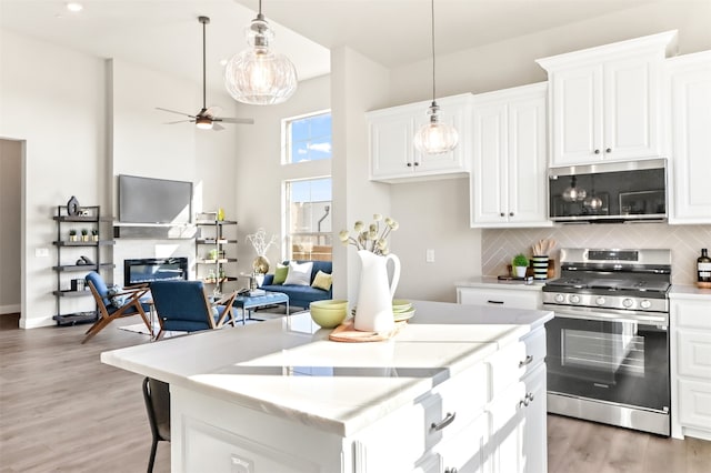 kitchen with stainless steel appliances, hanging light fixtures, and white cabinetry