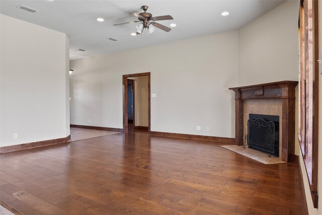 unfurnished living room featuring dark hardwood / wood-style flooring, a tile fireplace, and ceiling fan