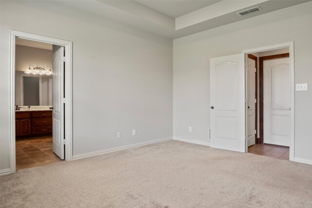 unfurnished bedroom featuring connected bathroom and carpet floors