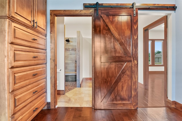 corridor featuring wood-type flooring and a barn door