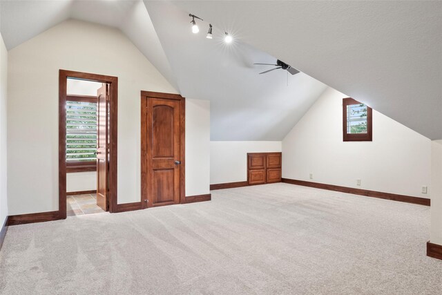 bonus room with ceiling fan, vaulted ceiling, and light colored carpet