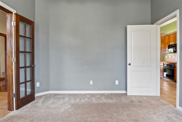 empty room featuring french doors and light tile patterned floors