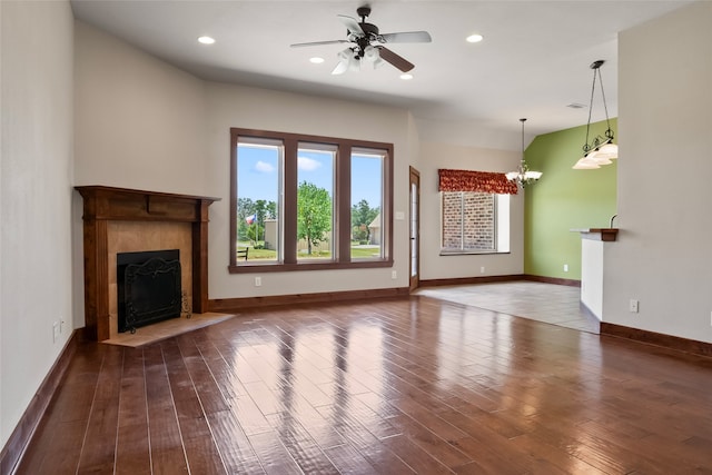 unfurnished living room with a fireplace, dark hardwood / wood-style flooring, and ceiling fan with notable chandelier