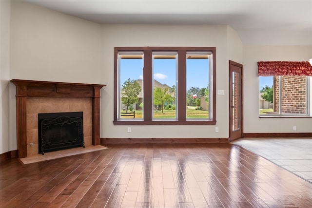 unfurnished living room featuring a tiled fireplace and wood-type flooring