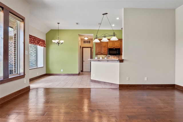 kitchen featuring tile patterned floors, pendant lighting, sink, an inviting chandelier, and backsplash