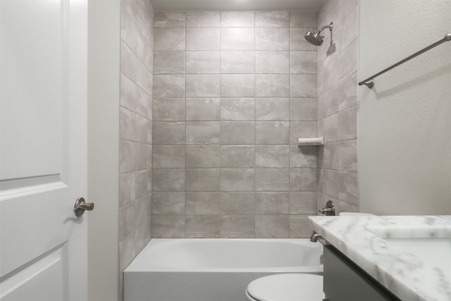 full bathroom featuring vanity, tiled shower / bath, and toilet