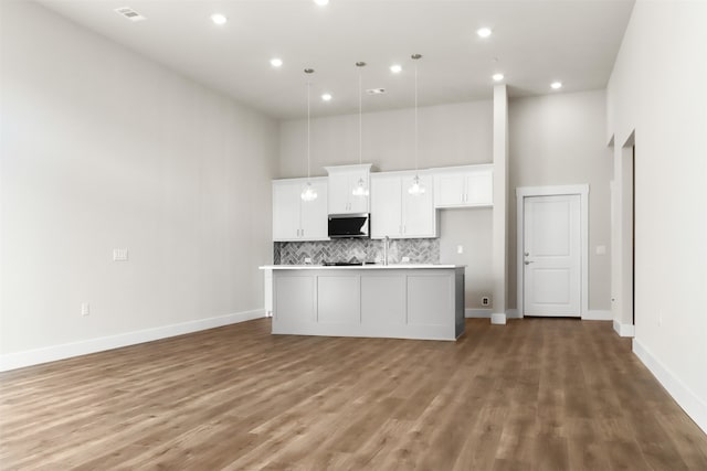 kitchen with white cabinets, hanging light fixtures, a center island with sink, and dark hardwood / wood-style floors