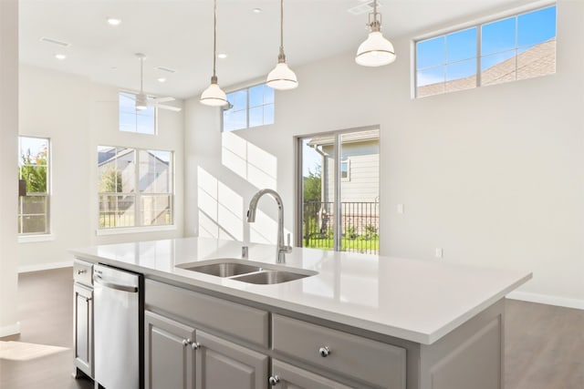 kitchen with hanging light fixtures, a center island with sink, dark hardwood / wood-style floors, gray cabinetry, and sink