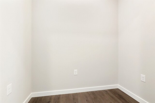 unfurnished room featuring baseboards and dark wood-style floors