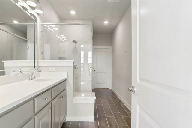 bathroom featuring recessed lighting, baseboards, a shower stall, and vanity