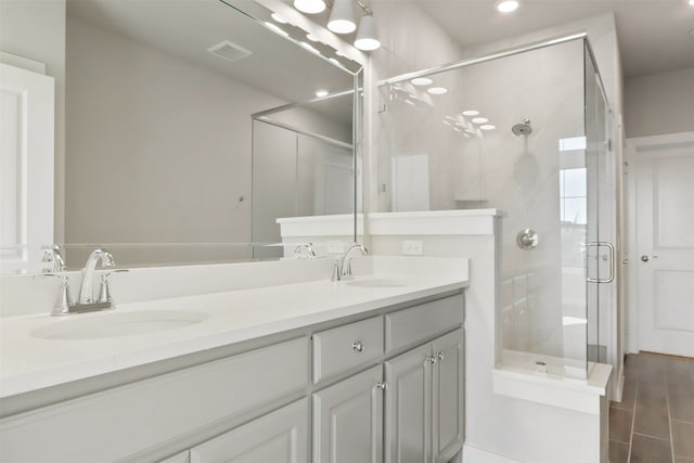 full bath featuring double vanity, visible vents, a shower stall, and a sink