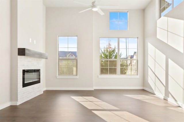 unfurnished living room with a high ceiling, wood-type flooring, and ceiling fan