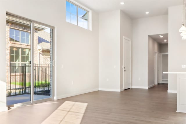 empty room featuring dark hardwood / wood-style flooring, plenty of natural light, and a high ceiling