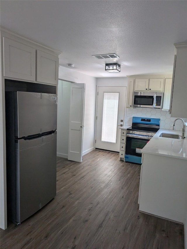 kitchen featuring backsplash, sink, dark hardwood / wood-style floors, appliances with stainless steel finishes, and white cabinetry