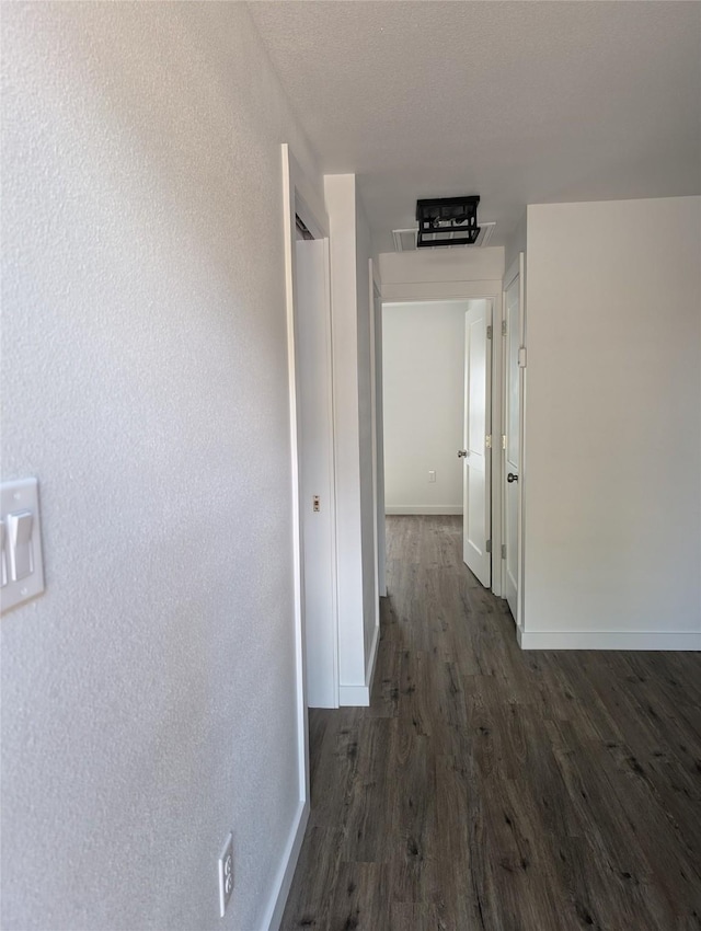 hall with a textured ceiling and dark hardwood / wood-style flooring