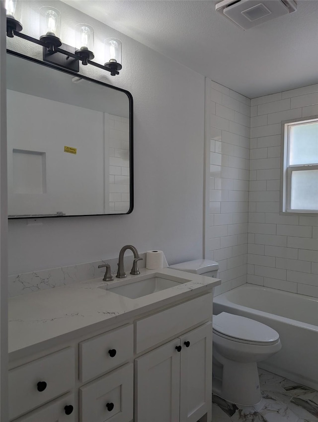 full bathroom with tiled shower / bath, vanity, and toilet