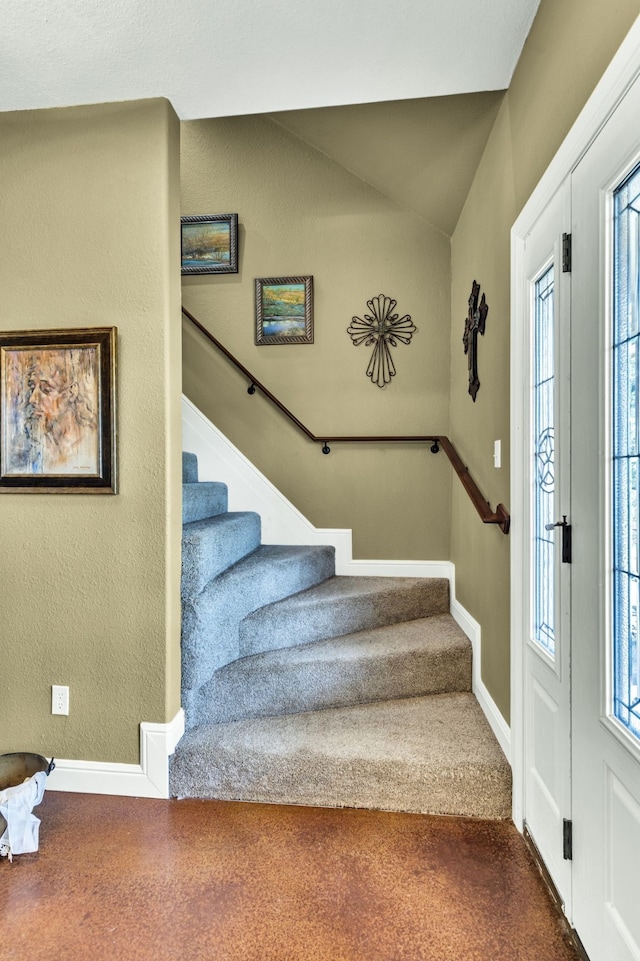 entrance foyer with lofted ceiling, carpet floors, and plenty of natural light