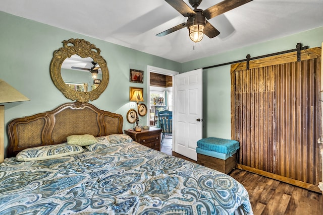 bedroom with hardwood / wood-style flooring, ceiling fan, and a barn door