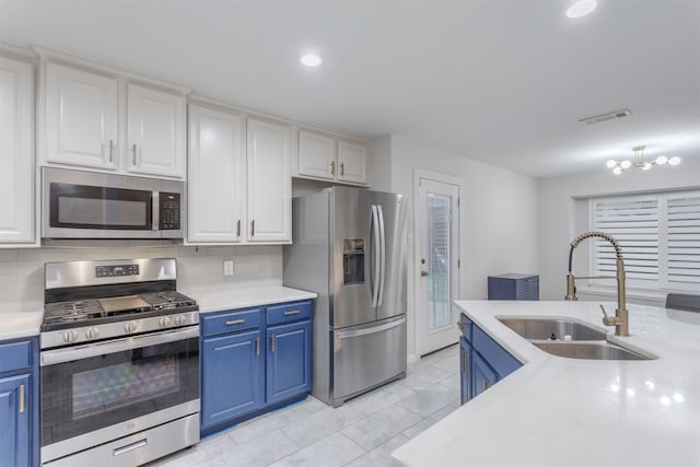 kitchen featuring white cabinetry, backsplash, blue cabinets, appliances with stainless steel finishes, and sink