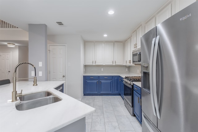 kitchen featuring white cabinetry, backsplash, stainless steel appliances, blue cabinetry, and sink